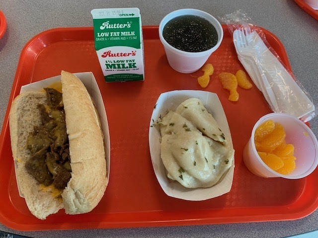  This lunch consists of a Philly cheesesteak, potato pierogies and mandarin oranges. 
